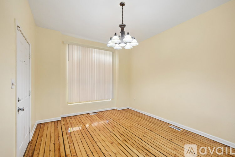 A room with wooden floors and a chandelier hanging from the ceiling.