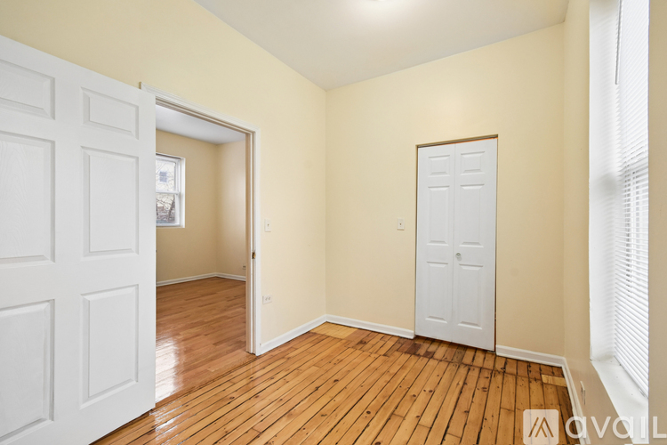 A room with a white door and wooden flooring.