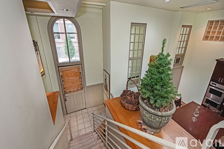 A room with a potted plant on a table and a staircase.
