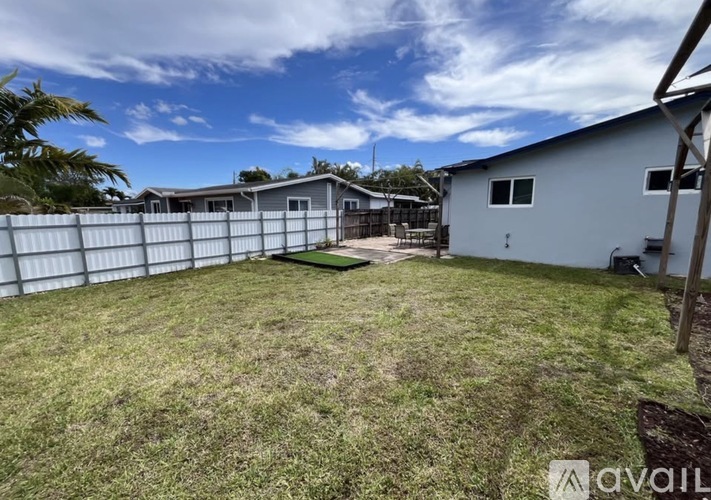 A backyard with a fence and a house in the background.