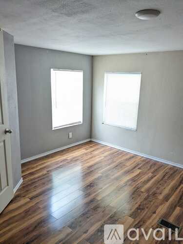 A room with wooden floors and two windows.