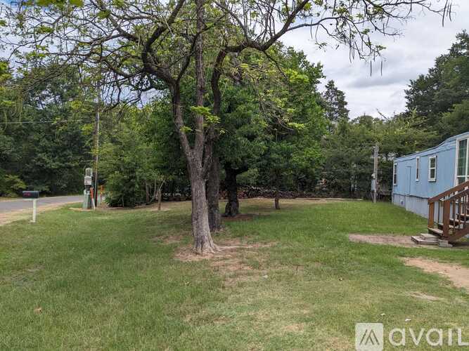 A tree in a grassy area with a house and a sign in the background.