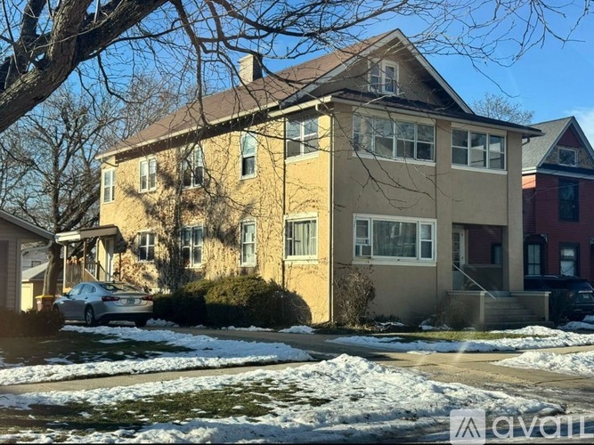 A beige house with a brown roof and a car parked in front.