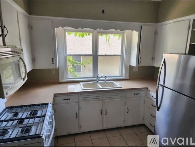 A kitchen with white cabinets and a stainless steel refrigerator.