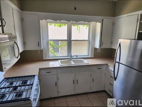 A kitchen with white cabinets and a stainless steel refrigerator.