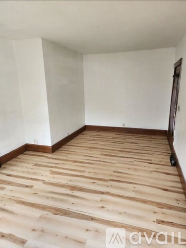 A room with wooden flooring and white walls.