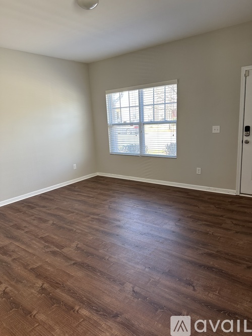 A room with wooden flooring and a window with blinds.