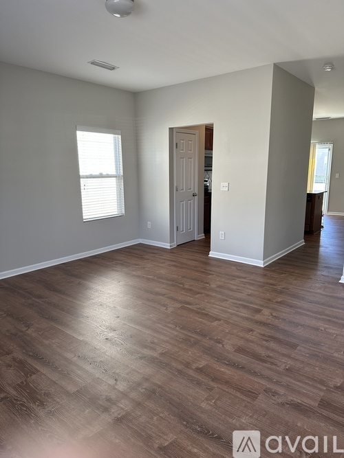 A room with wooden flooring and a door leading to another room.