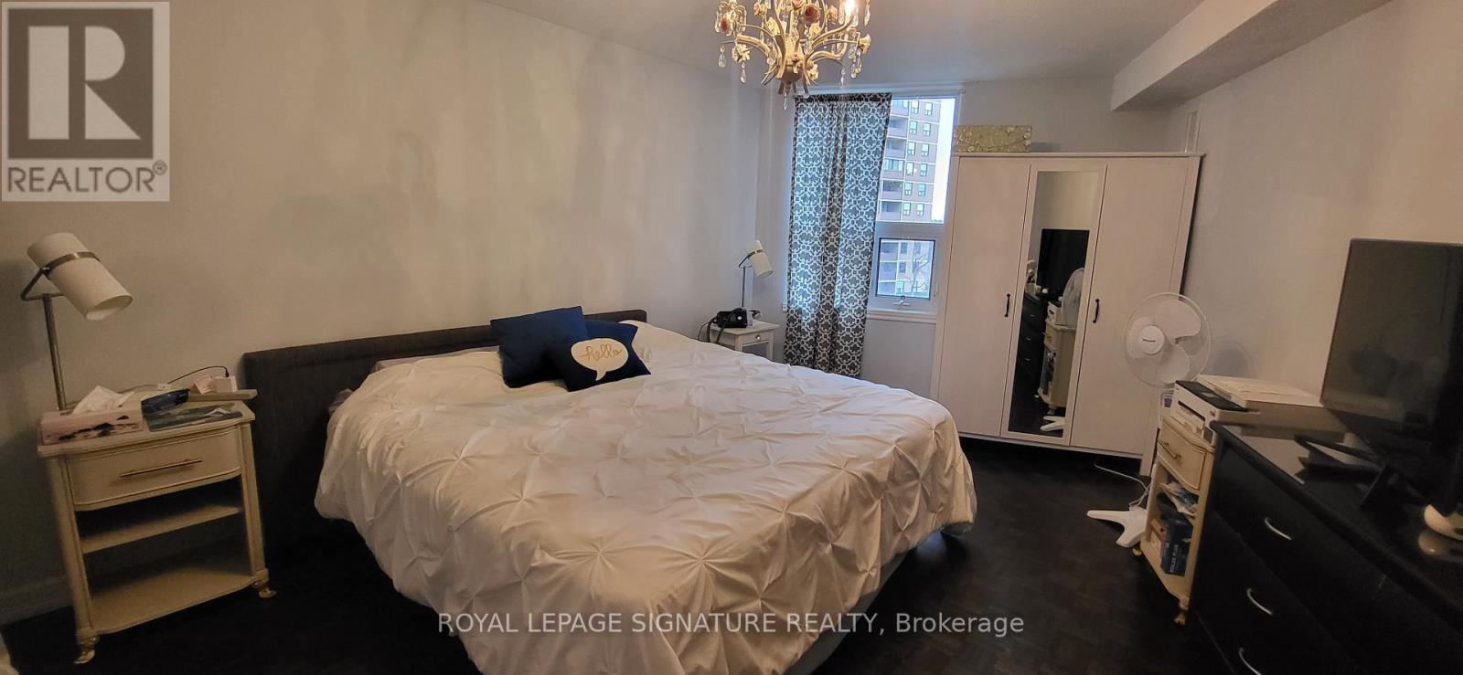 A bedroom with a large bed and a chandelier.