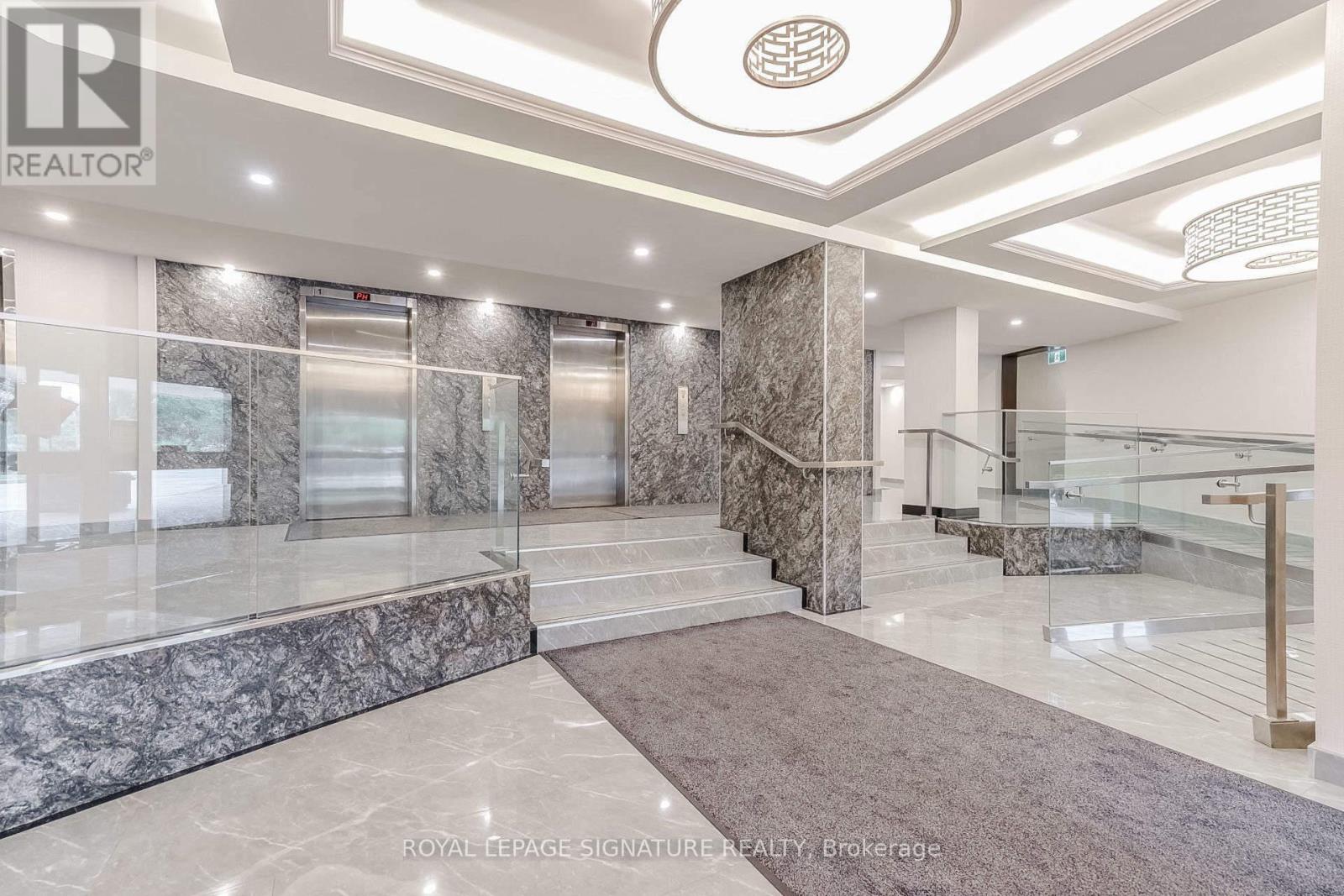 A spacious lobby with marble floors and a staircase.