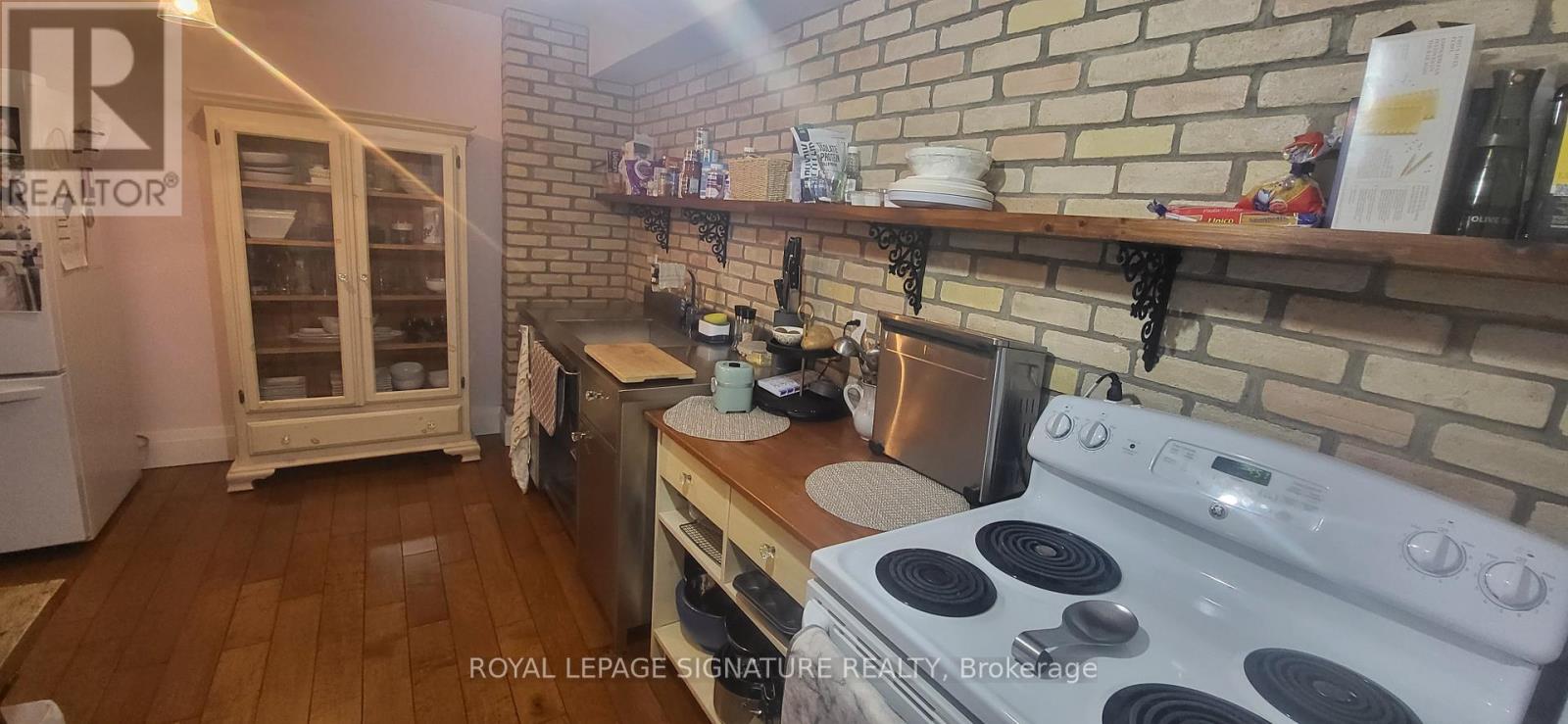 A kitchen with a white stove and wooden floors.