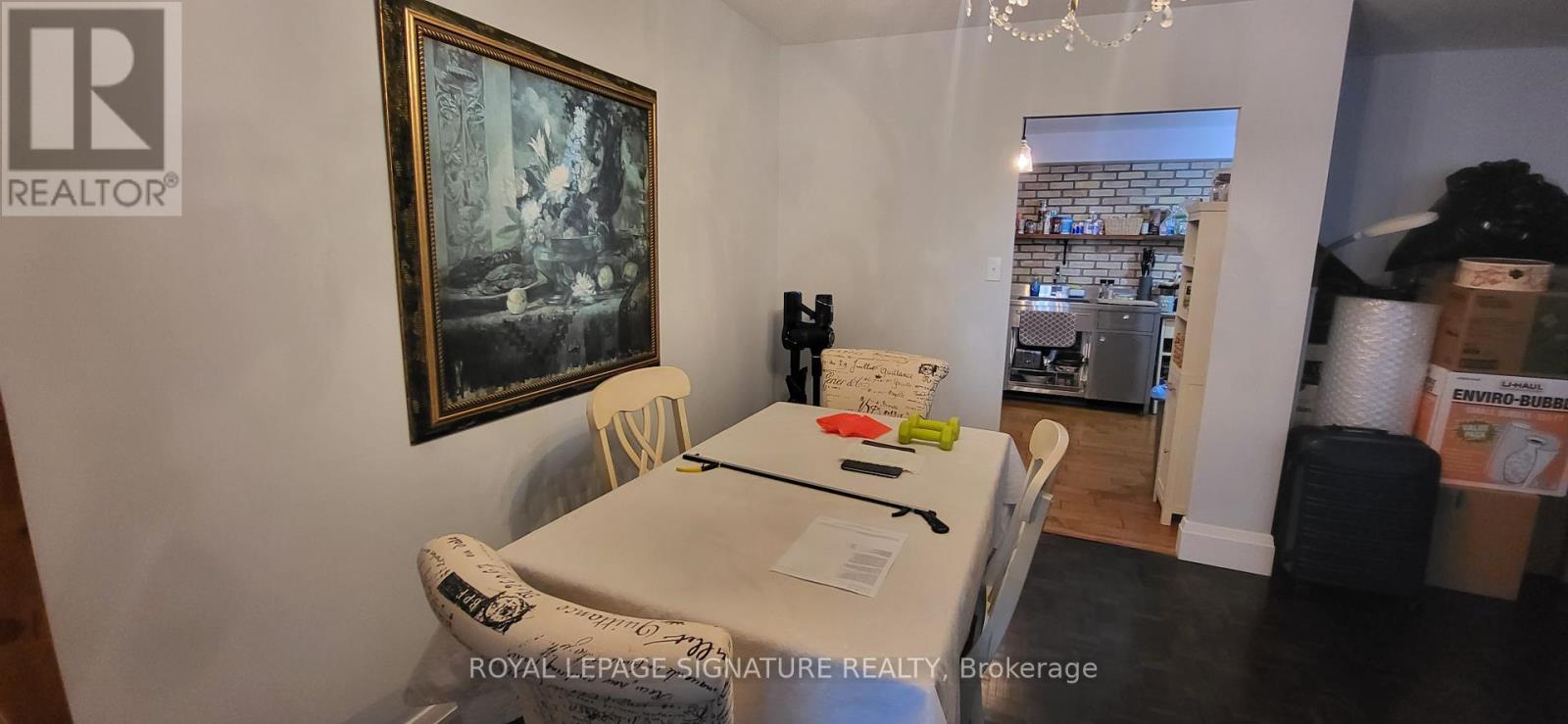 A dining room with a white table and chairs and a painting on the wall.