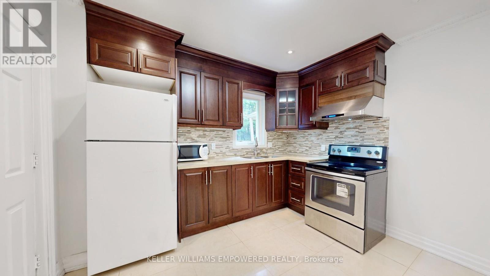 A white refrigerator in a kitchen with brown cabinets and a stone backsplash.
