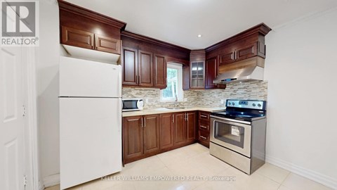 A white refrigerator in a kitchen with brown cabinets and a stone backsplash.