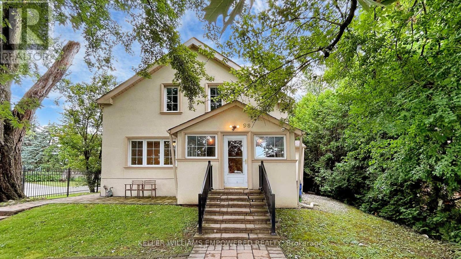A small house with a front porch is surrounded by greenery.