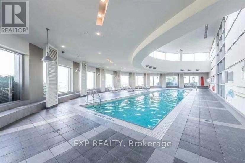A large indoor swimming pool with a tiled floor and a sunlit atrium.