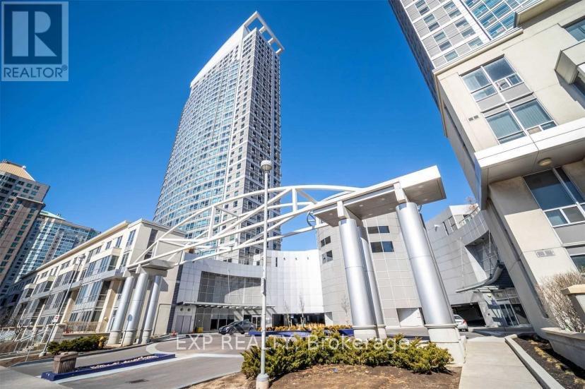 A modern building with a glass facade stands tall among other buildings.