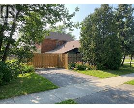 A house with a brown fence and green trees in front.