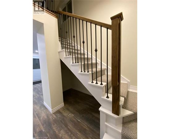 A staircase with a wooden handrail and white risers.