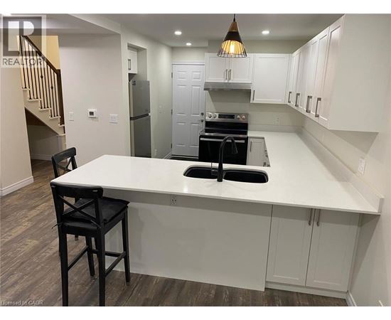 A kitchen with a white countertop and black bar stools.