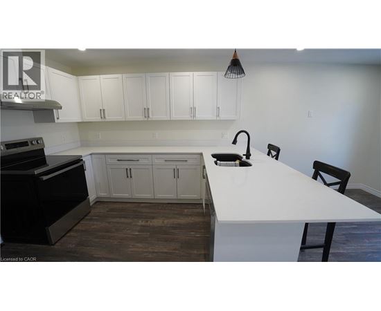 A kitchen with white countertops and black appliances.