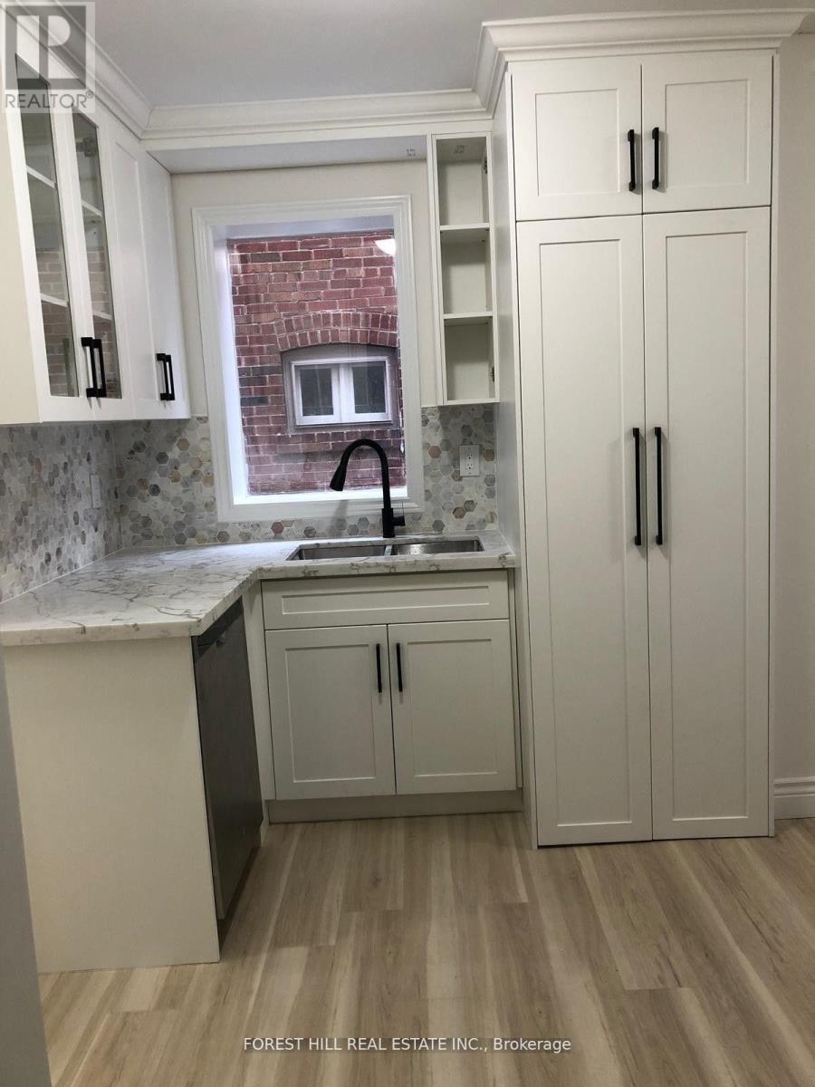 A kitchen with white cabinets and a brick wall.