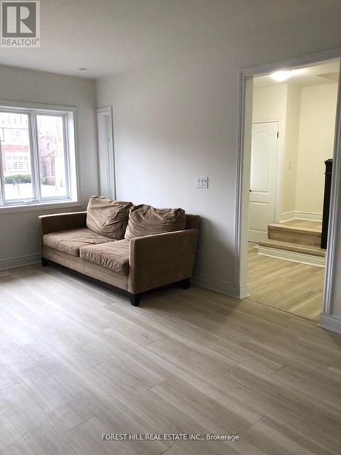 A living room with a couch and a doorway leading to another room.