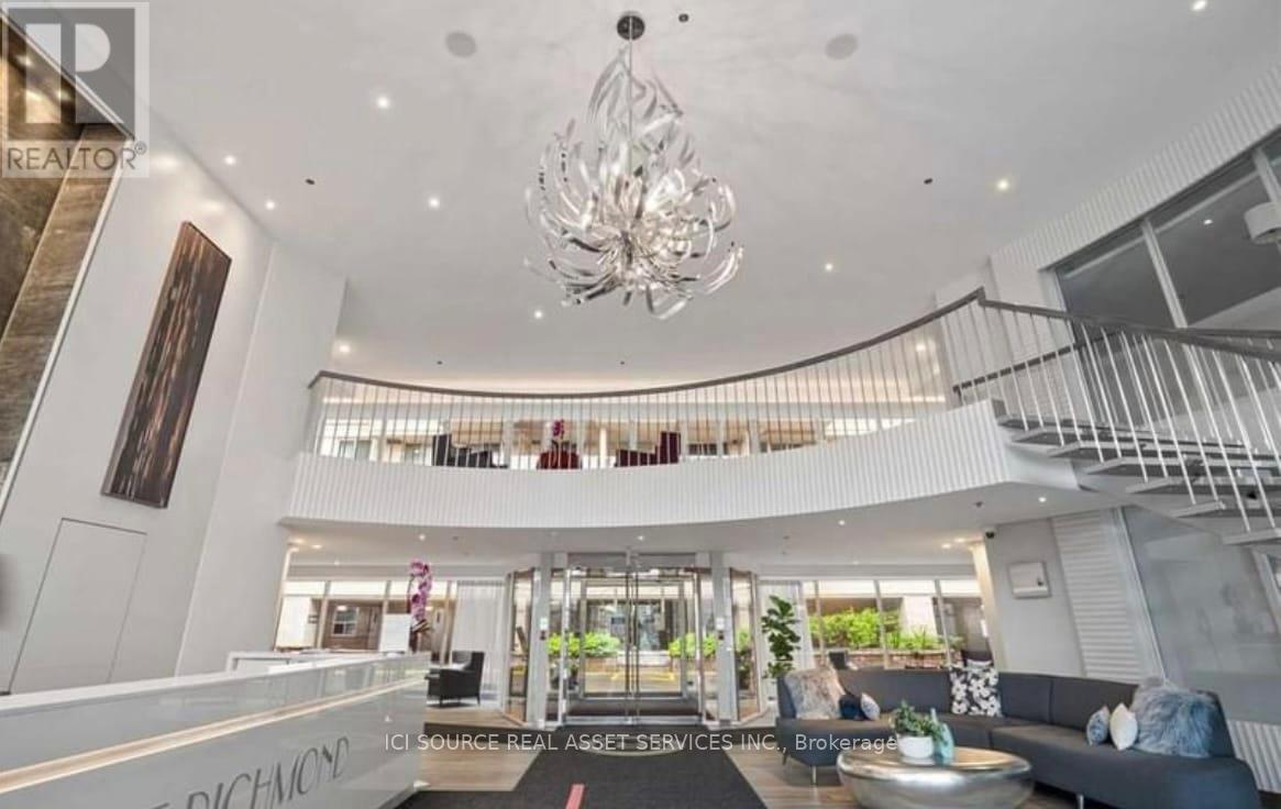 A large, modern living room with a staircase and a chandelier.