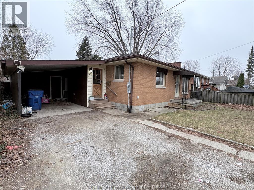 A house with a brown brick exterior and a gravel driveway.