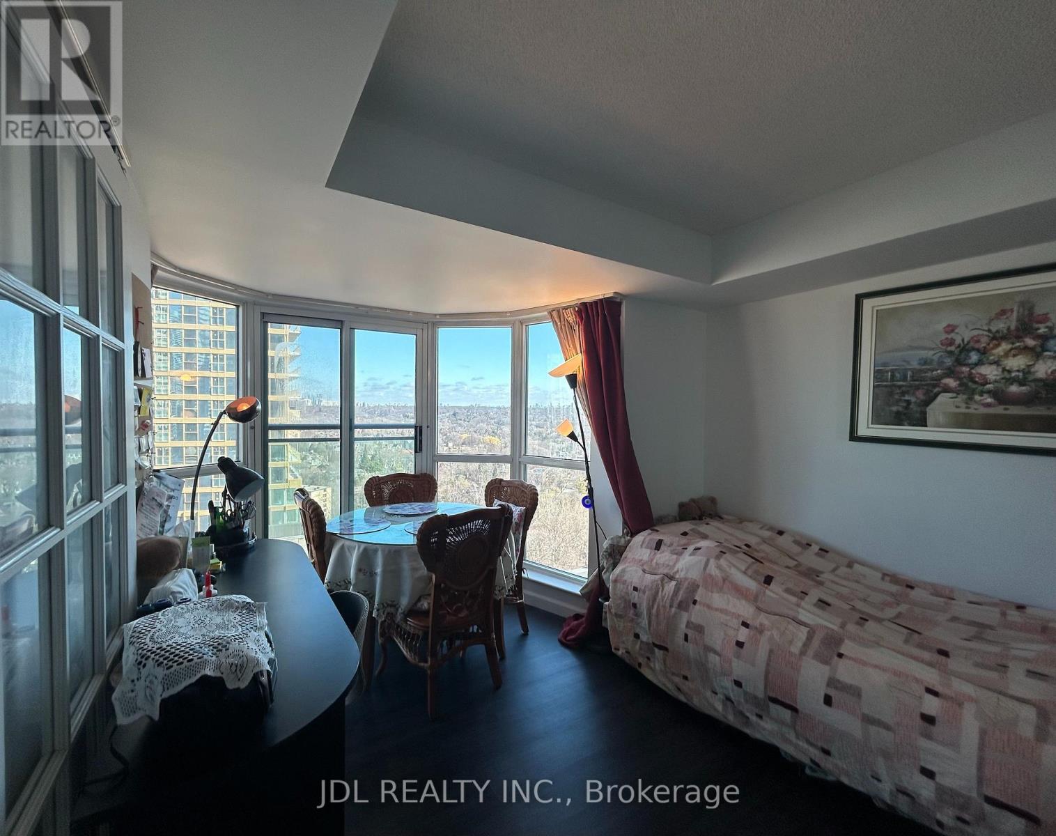 A bedroom with a bed, table, chairs and a view of the city.