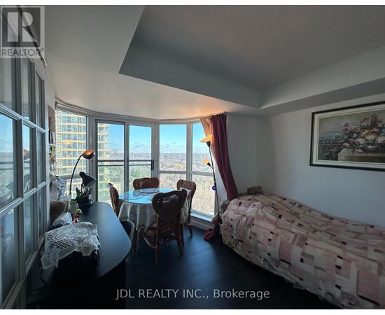 A bedroom with a bed, table, chairs and a view of the city.