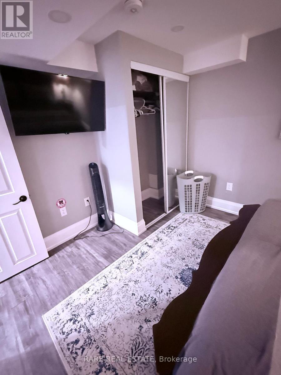 A bedroom with a bed, a TV, a heater and a wall-mounted fan.