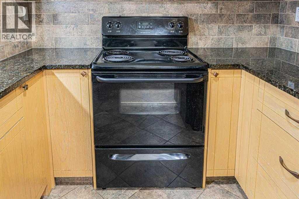 A black oven with a stainless steel handle is in a kitchen with wooden cabinets.