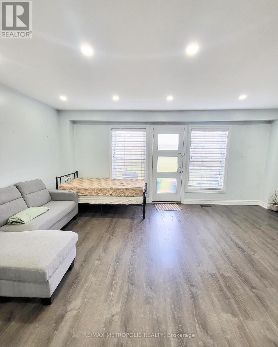 A bedroom with a bed, a couch, and a window with blinds.