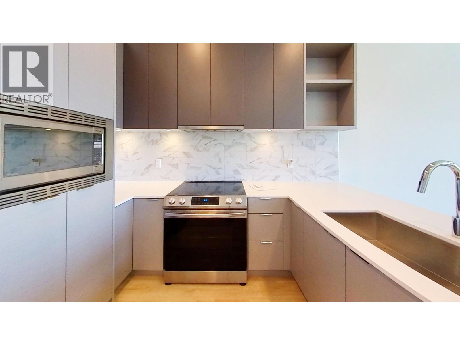 A modern kitchen with a stove top oven and a sink.