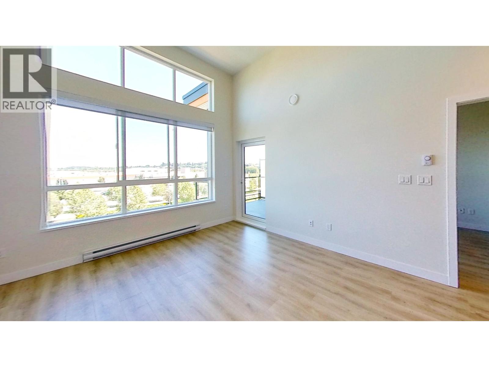 A large empty room with a window overlooking a cityscape.