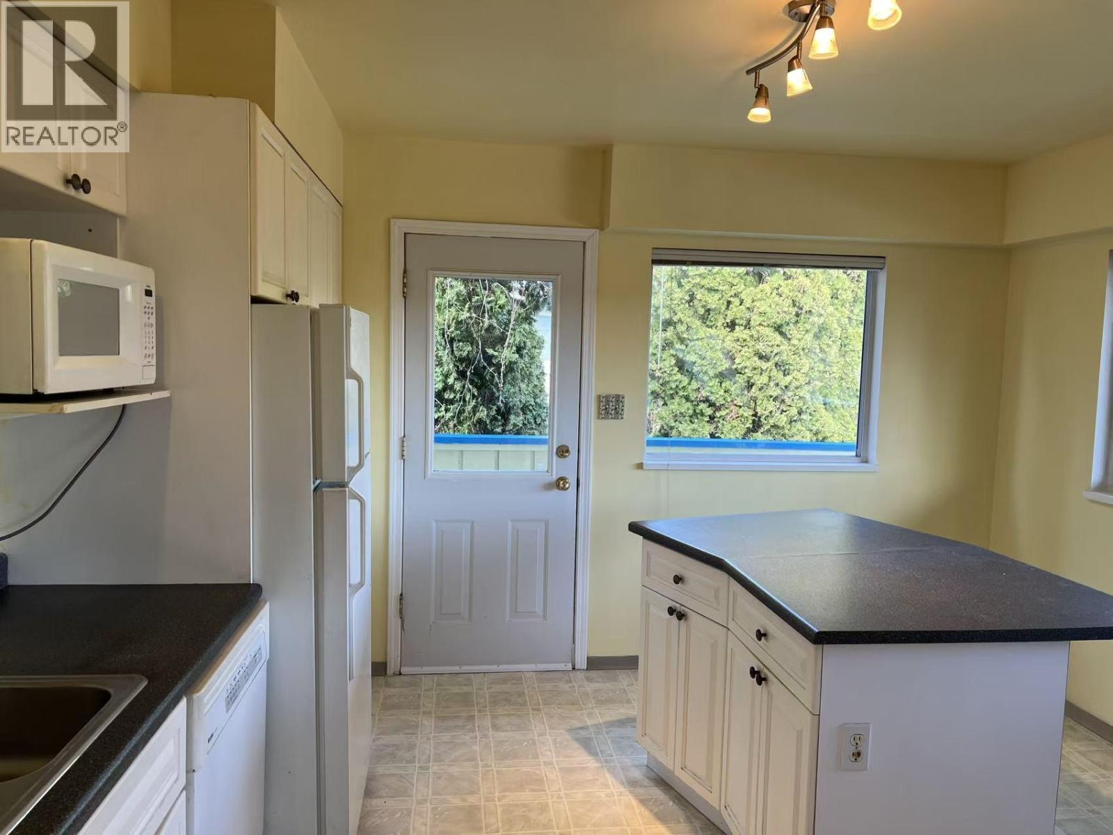 A kitchen with a black countertop and white cabinets.