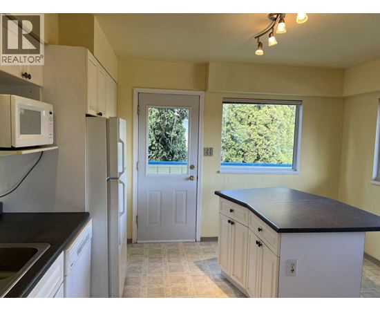 A kitchen with a black countertop and white cabinets.