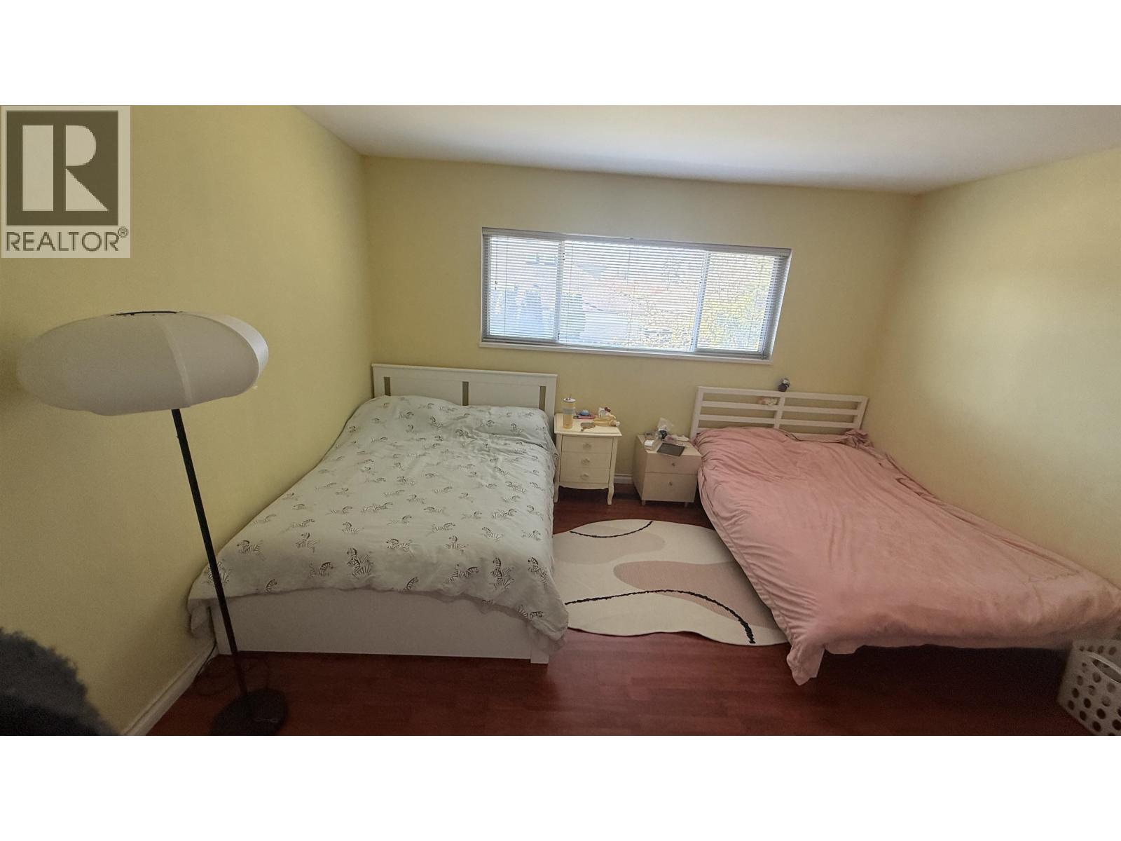A bedroom with two beds, one with a pink bedspread and the other with a floral pattern.