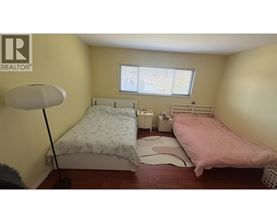 A bedroom with two beds, one with a pink bedspread and the other with a floral pattern.