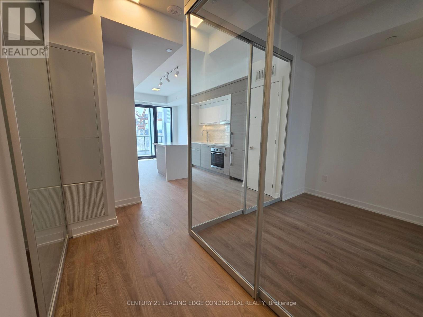 A spacious room with wooden flooring and a large mirror on the wall.