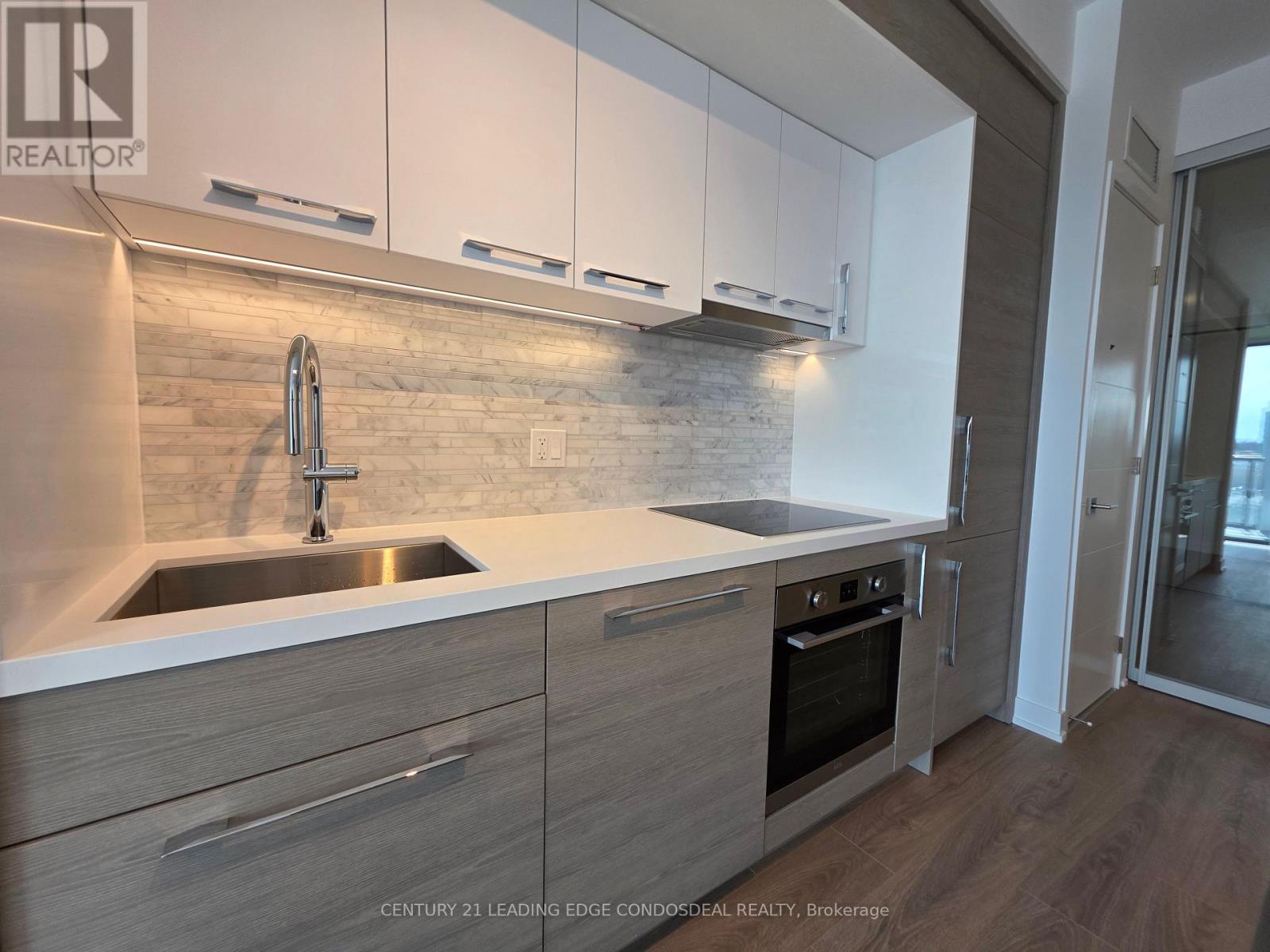 A modern kitchen with a stainless steel sink and wooden cabinets.
