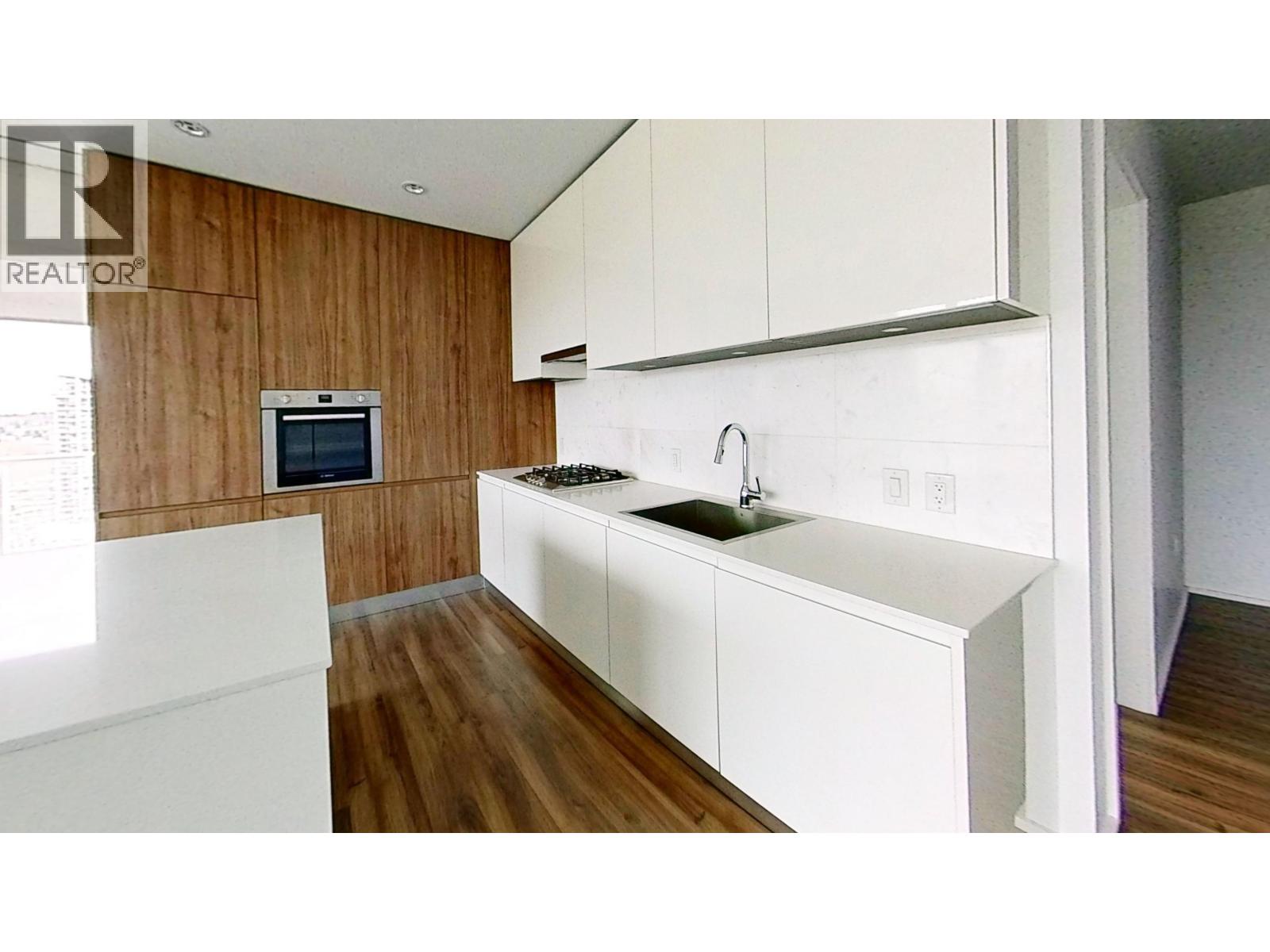 A modern kitchen with white countertops and wooden walls.