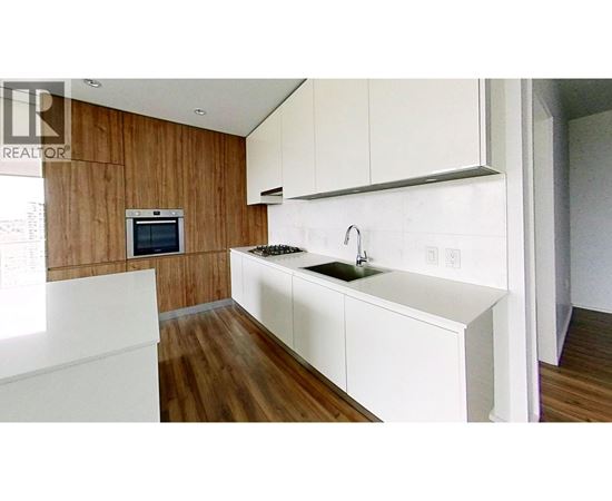 A modern kitchen with white countertops and wooden walls.