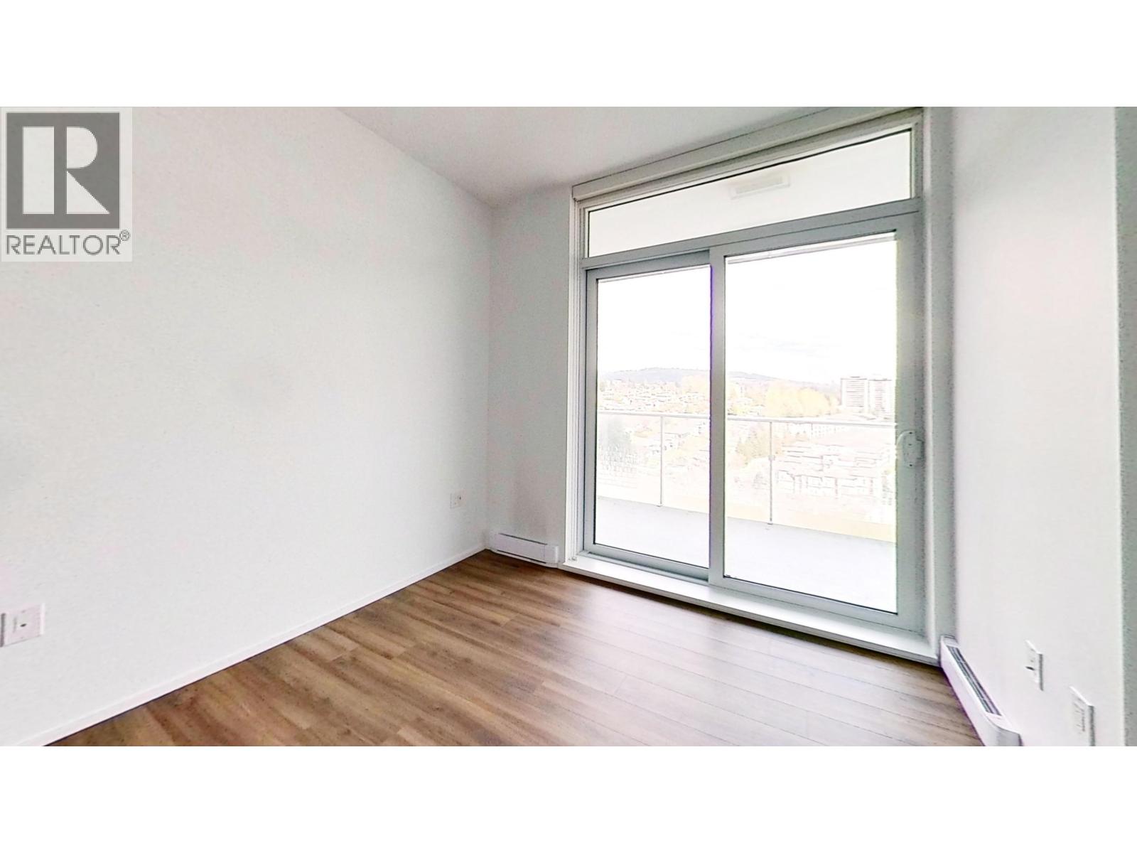 A room with a large window and wooden flooring.