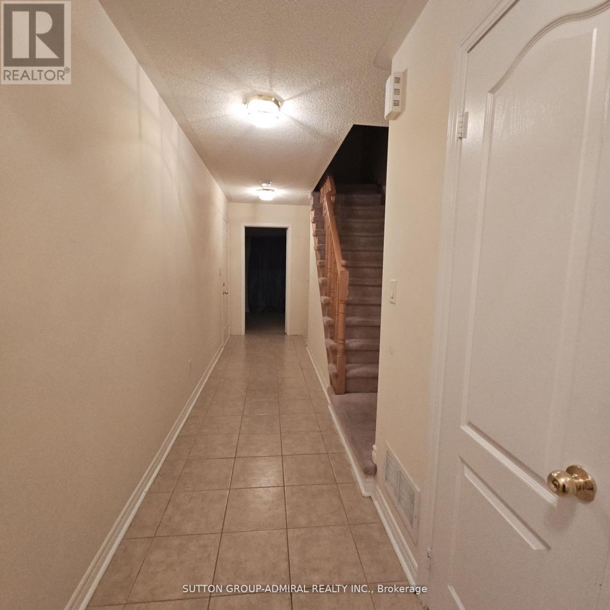 A hallway with a staircase in the background.
