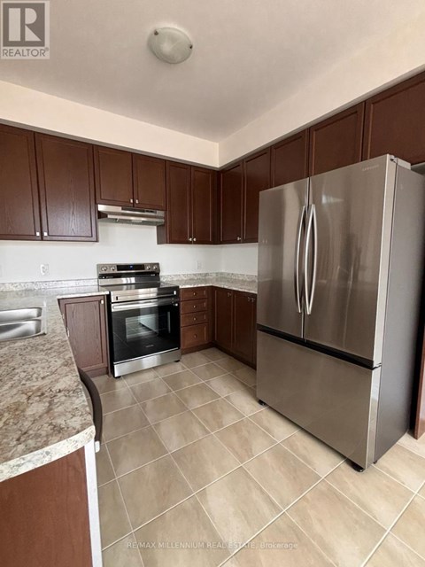 A kitchen with brown cabinets and a stainless steel refrigerator.