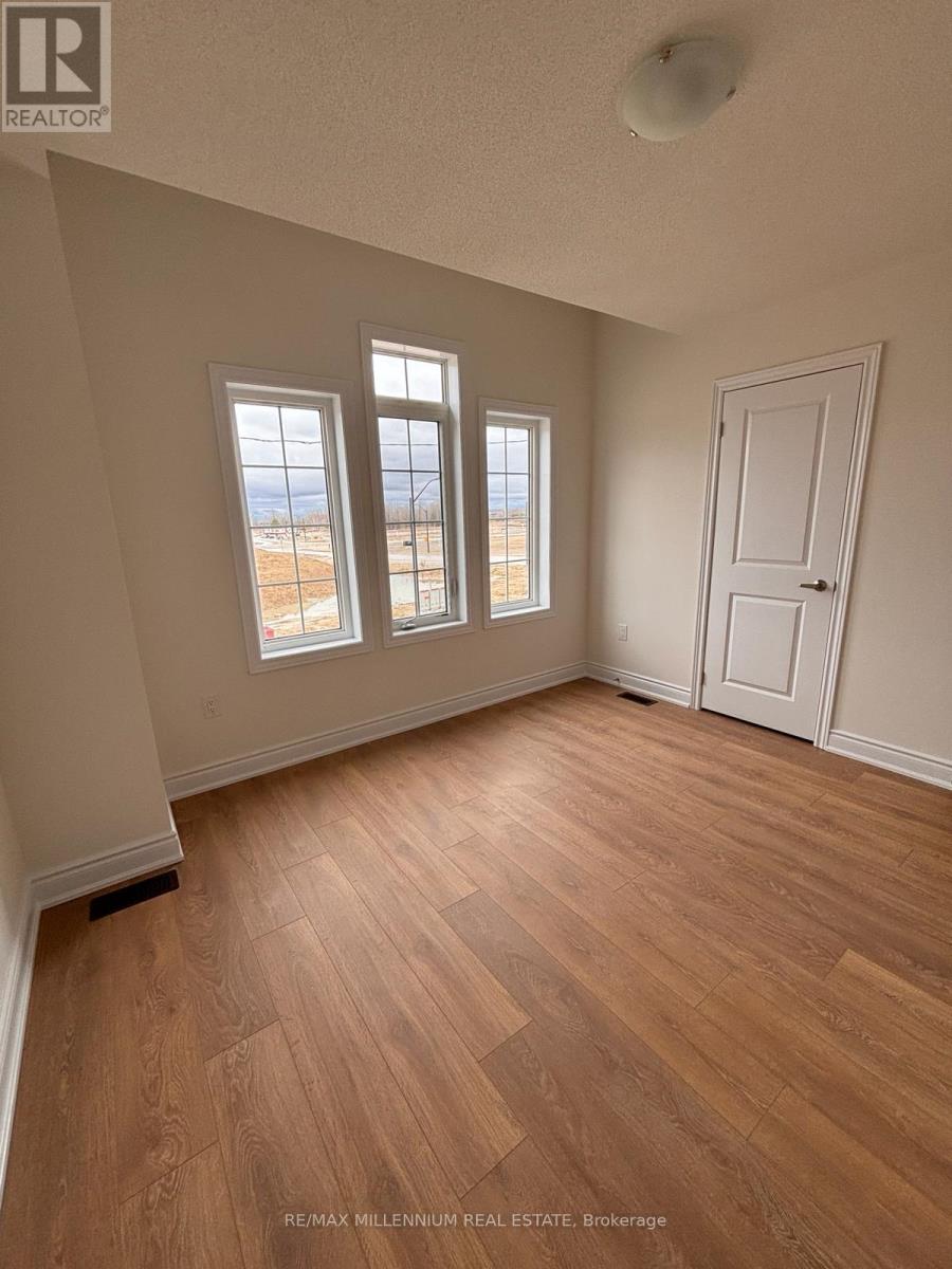 A room with wooden flooring and three windows.
