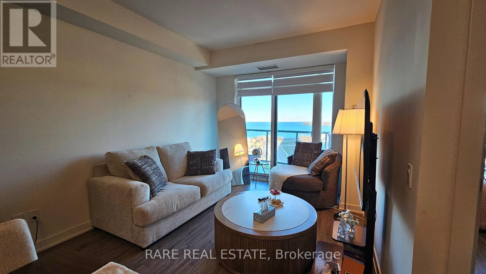 A living room with a couch, a table, and a view of the ocean.