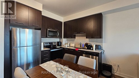 A kitchen with dark brown cabinets and a stainless steel refrigerator.